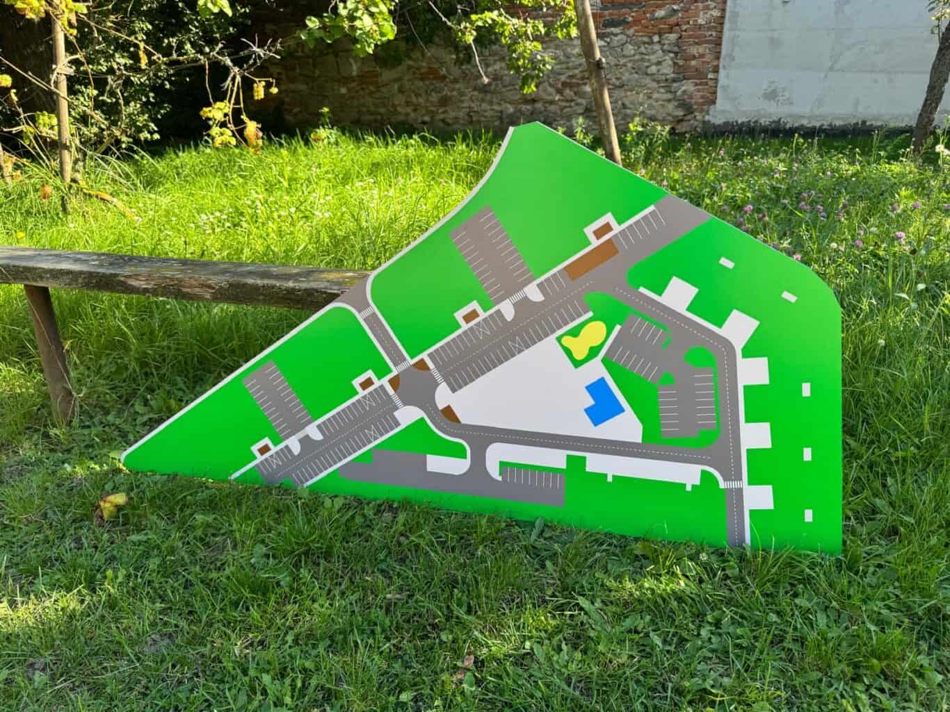 Model mestského parku s parkoviskom a hernými zónami, zelené plochy a chodníky.