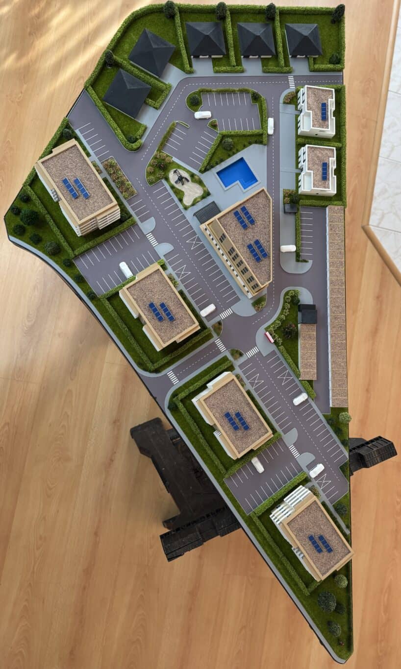 Model moderného komplexu s parkoviskom, bazénom a viacerými budovami.
