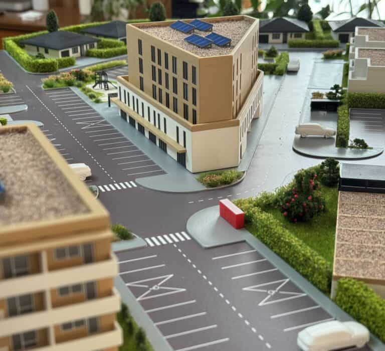 Model moderného kancelárskeho komplexu s solárnymi panelmi na streche.