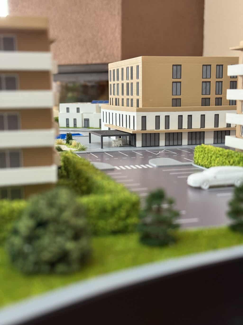 Moderné modelové mesto s parkoviskom a zelenými plochami, ukazuje detailný model architektúry a urba.