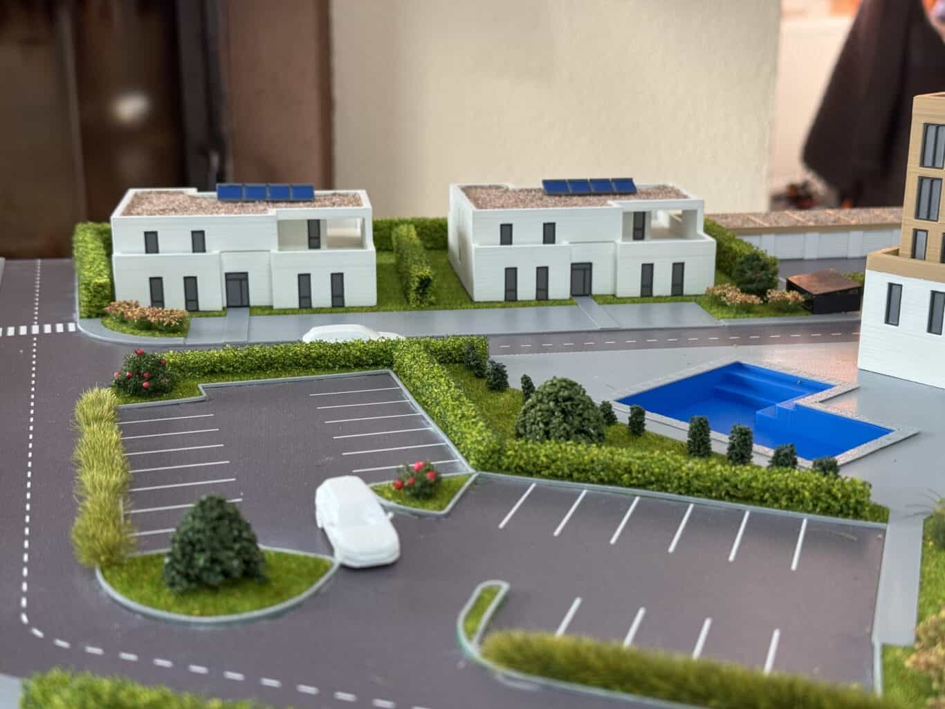 Model moderného bytového komplexu s parkovacou zónou a upravenou zeleňou.